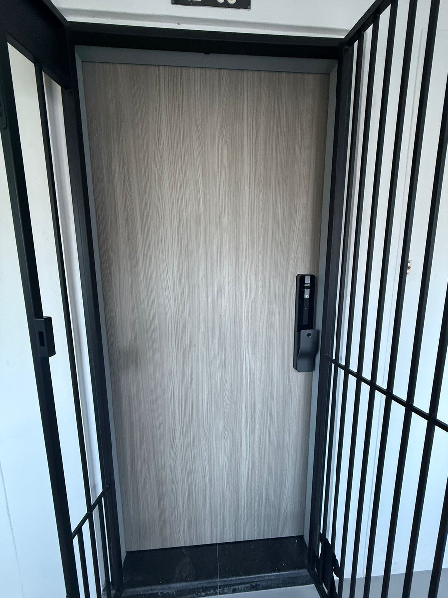 Wood-grain main door with black metal gate, installed by Door Empire Singapore